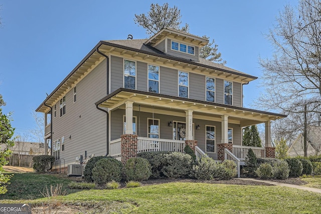 traditional style home with a porch, central AC, and a front lawn