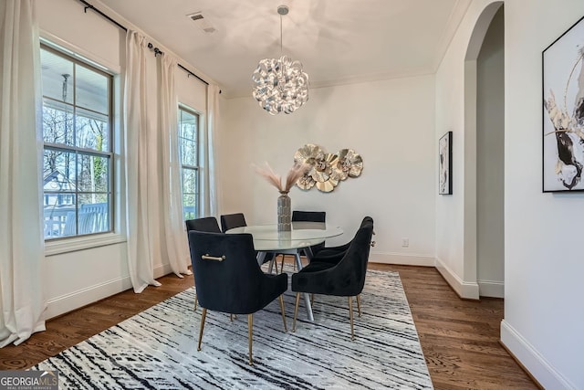 dining area with dark wood-style floors, arched walkways, visible vents, and baseboards