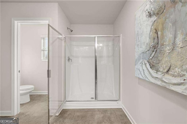 full bathroom featuring a shower stall, toilet, and baseboards