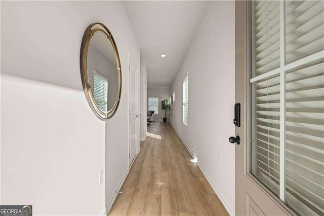 hallway featuring light wood finished floors, baseboards, and recessed lighting