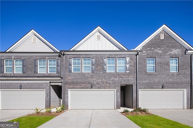 view of property with board and batten siding, brick siding, driveway, and a garage