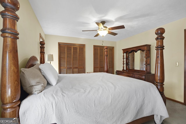 carpeted bedroom featuring baseboards, two closets, and ceiling fan