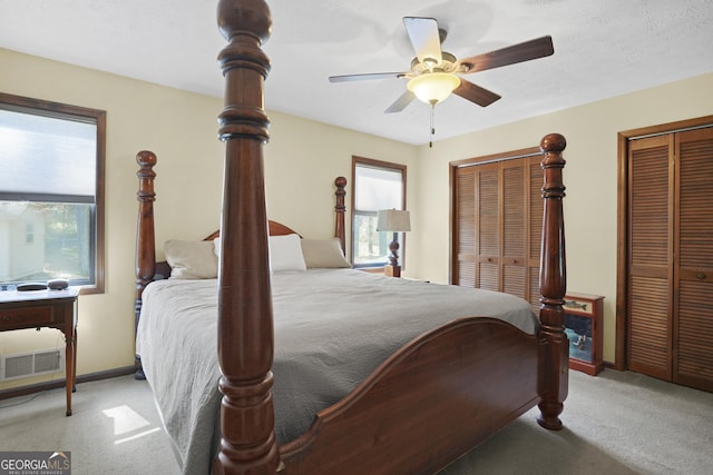 carpeted bedroom with a ceiling fan, baseboards, two closets, and a textured ceiling