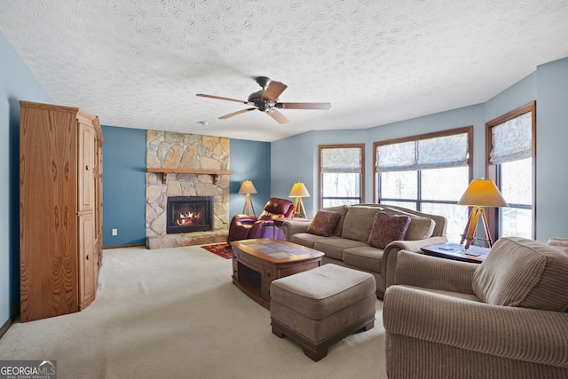 living area with a stone fireplace, a textured ceiling, light colored carpet, and a ceiling fan