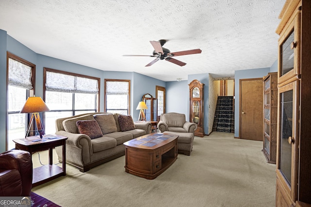 living room featuring light colored carpet, a ceiling fan, and a textured ceiling