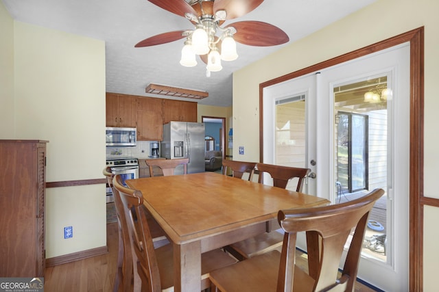 dining space featuring a textured ceiling, wood finished floors, and a ceiling fan