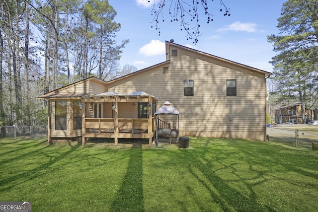 rear view of property with a gate, a lawn, a deck, and fence