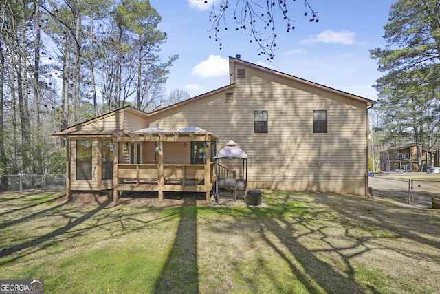 back of property with a deck, a gate, fence, and a lawn