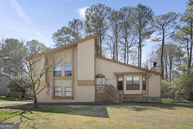 view of front of home featuring a front yard, a chimney, and fence