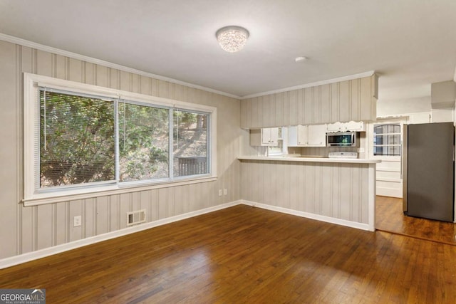 kitchen featuring visible vents, dark wood-style flooring, a peninsula, stainless steel appliances, and light countertops