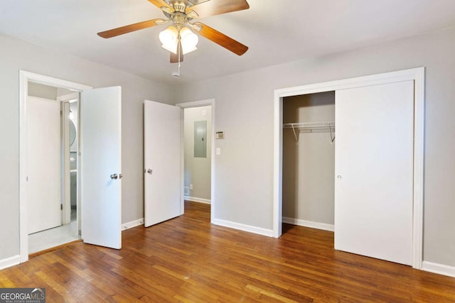 unfurnished bedroom with a closet, ceiling fan, wood finished floors, electric panel, and baseboards