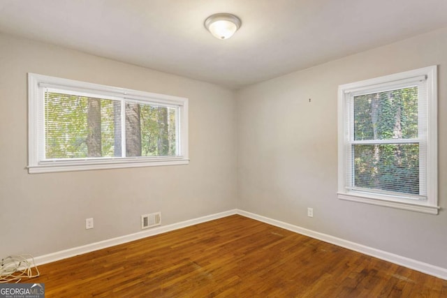 spare room with visible vents, baseboards, and wood finished floors