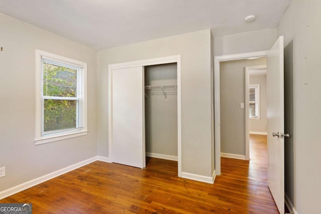 unfurnished bedroom featuring a closet, wood finished floors, and baseboards