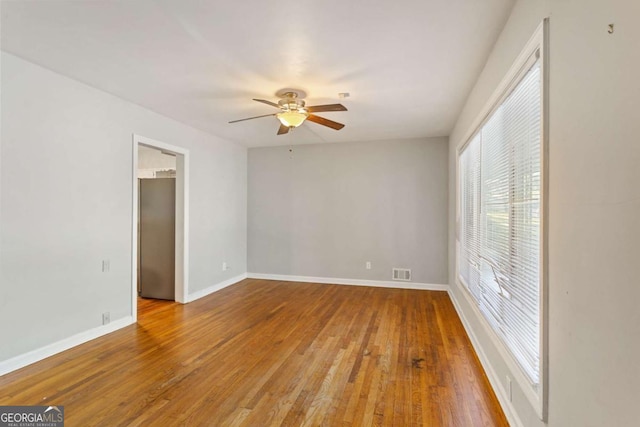 empty room featuring baseboards, visible vents, ceiling fan, and wood finished floors