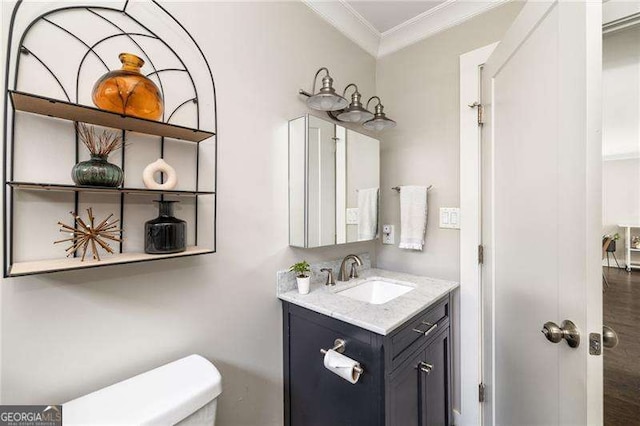 half bathroom featuring ornamental molding, vanity, and toilet