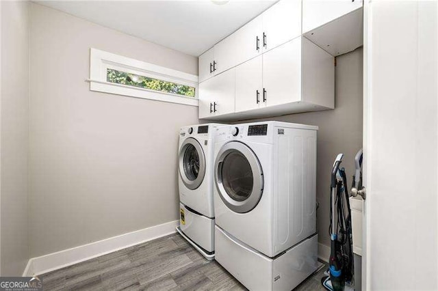 laundry area featuring cabinet space, washer and clothes dryer, baseboards, and wood finished floors