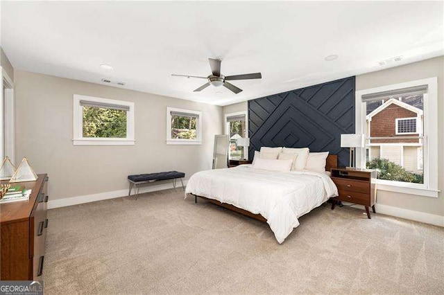 bedroom with visible vents, baseboards, a ceiling fan, and light colored carpet