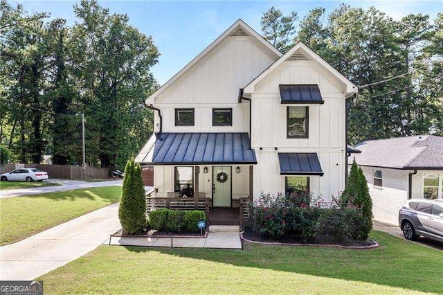 modern farmhouse with metal roof, a porch, board and batten siding, a standing seam roof, and a front yard