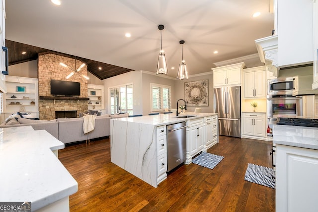 5230 Harris Springs Dr, Cumming, GA 30040 - kitchen featuring appliances with stainless steel finishes, a sink, vaulted ceiling, white cabinets, and light stone counters