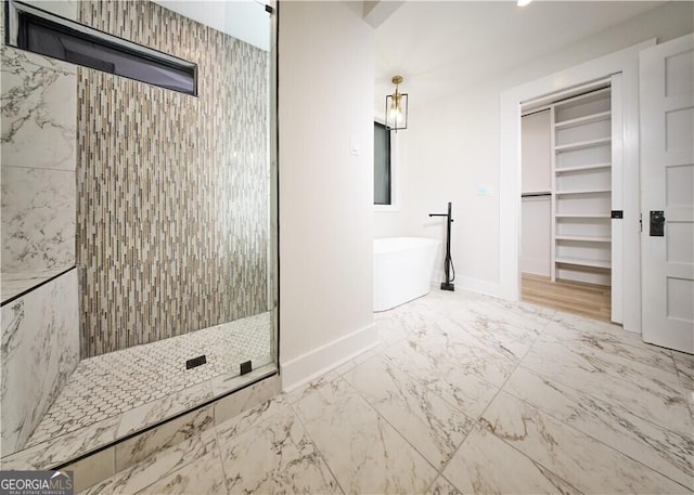 bathroom with baseboards, a freestanding bath, a walk in closet, a shower stall, and marble finish floor