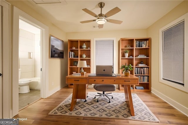 office area with light wood-style floors, baseboards, and a ceiling fan