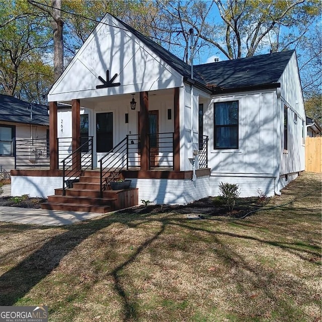bungalow-style house featuring a shingled roof, a front lawn, and covered porch