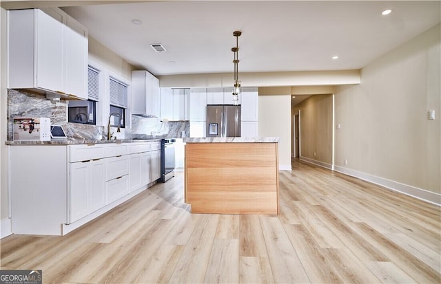 kitchen featuring stainless steel fridge with ice dispenser, visible vents, a center island, white cabinets, and range