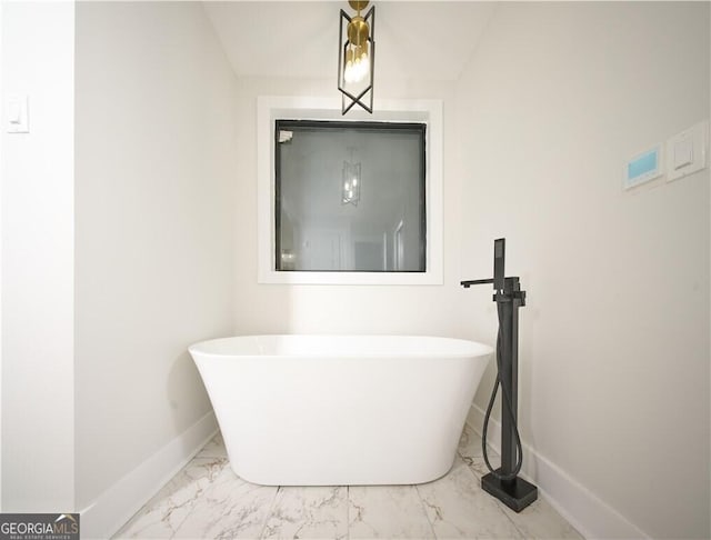 bathroom featuring a soaking tub, marble finish floor, and baseboards