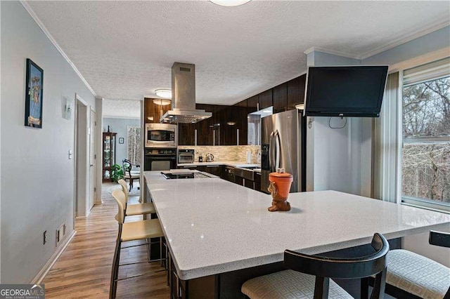 2590 Runic Way, Johns Creek, GA 30022 - kitchen featuring black appliances, island exhaust hood, crown molding, light wood-style floors, and a breakfast bar
