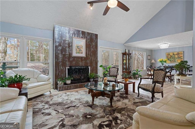 living room featuring a fireplace, lofted ceiling, ceiling fan, a textured ceiling, and wood finished floors