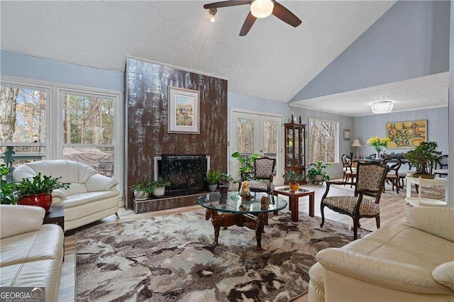 2590 Runic Way, Johns Creek, GA 30022 - living area featuring a textured ceiling, ceiling fan, wood finished floors, a large fireplace, and high vaulted ceiling