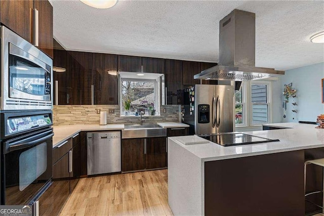 2590 Runic Way, Johns Creek, GA 30022 - kitchen featuring black appliances, island range hood, light countertops, light wood finished floors, and a textured ceiling
