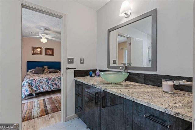 ensuite bathroom with a ceiling fan, connected bathroom, a textured ceiling, and vanity