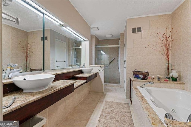 bathroom featuring visible vents, a sink, tile walls, and a shower stall