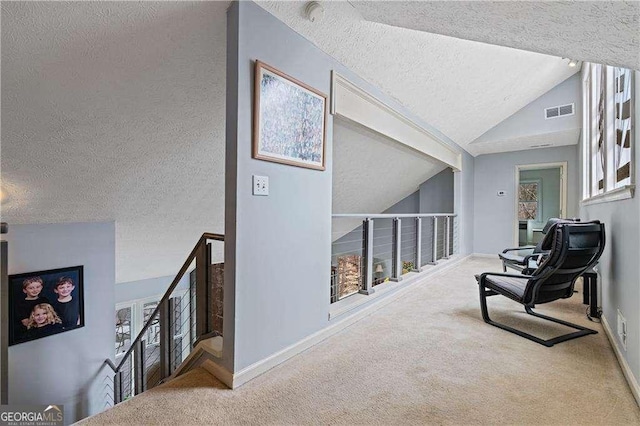 hall with lofted ceiling, an upstairs landing, visible vents, baseboards, and carpet