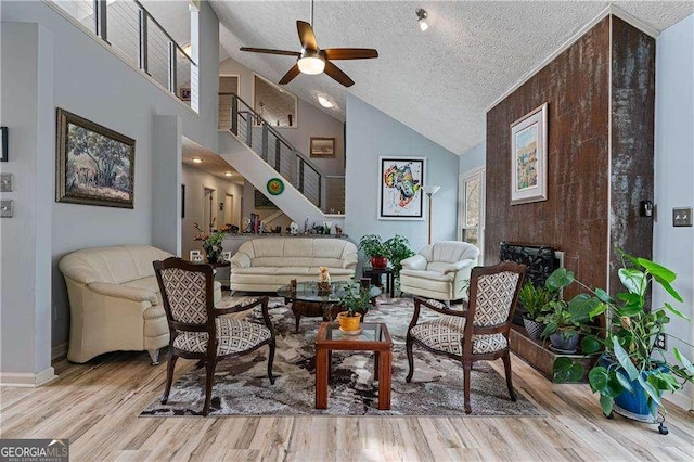 living area with ceiling fan, a fireplace, a textured ceiling, and wood finished floors