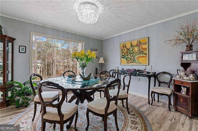 dining space featuring a chandelier, crown molding, a textured ceiling, and light wood finished floors