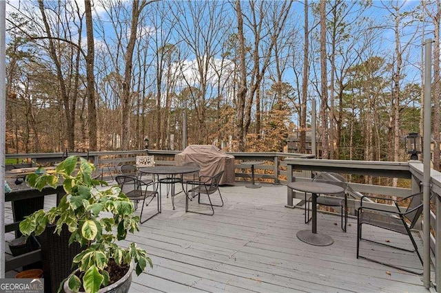 wooden terrace with a grill and outdoor dining area