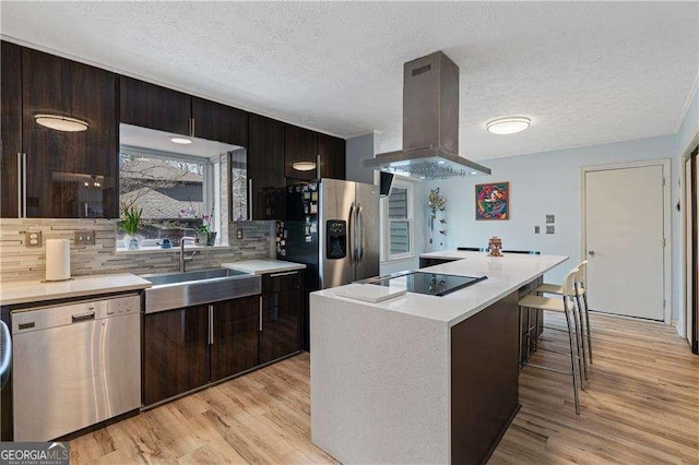 2590 Runic Way, Johns Creek, GA 30022 - kitchen featuring island range hood, stainless steel appliances, light countertops, light wood-style floors, and a textured ceiling