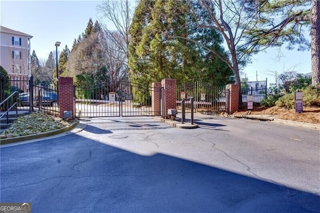 view of road with a gate, curbs, a gated entry, and street lights