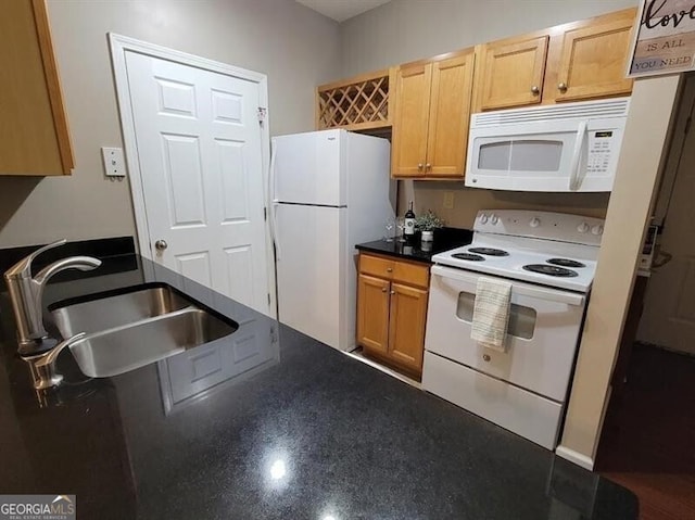 kitchen with dark countertops, white appliances, and a sink