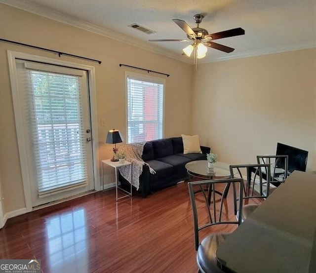 living area featuring crown molding, visible vents, ceiling fan, and wood finished floors