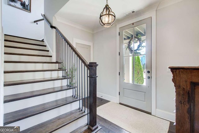 entrance foyer featuring baseboards, visible vents, dark wood-style floors, ornamental molding, and stairs