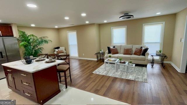 living room with recessed lighting, light wood-style floors, and baseboards