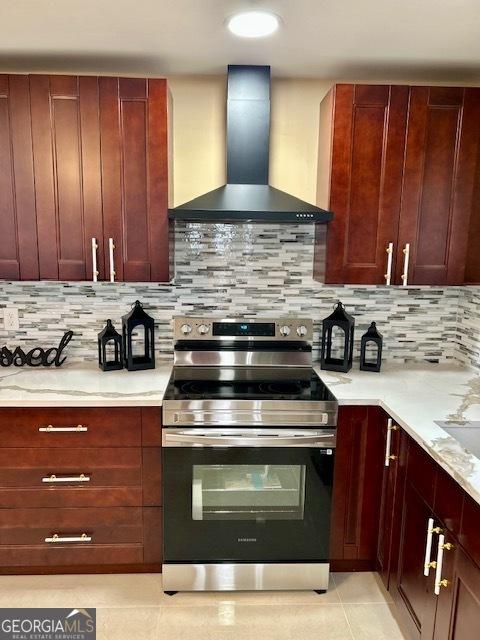 kitchen with stainless steel electric stove, light tile patterned flooring, wall chimney range hood, decorative backsplash, and dark brown cabinets