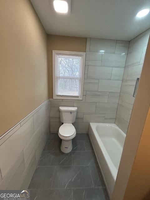 full bathroom featuring toilet and wainscoting