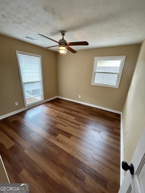 unfurnished room with visible vents, a ceiling fan, a textured ceiling, wood finished floors, and baseboards