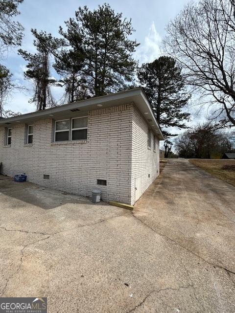 view of side of home featuring crawl space and brick siding