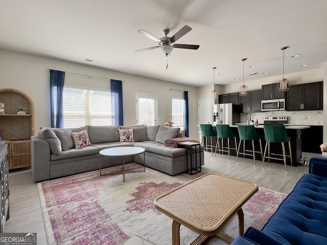 living room featuring ceiling fan, light wood-style flooring, and visible vents