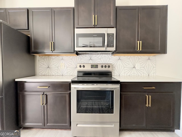 kitchen with stainless steel appliances, tasteful backsplash, light wood-type flooring, and light countertops